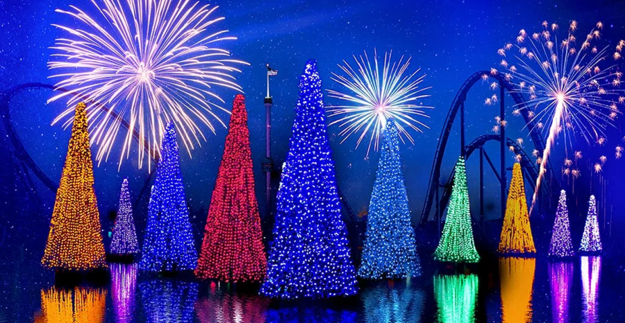 Bunte Weihnachtsbäume auf einem See, darüber Feuerwerk